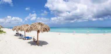Varadero, Küba - 8 Mayıs 2019: Canlı güneşli bir günde gölge şemsiyenin altındaki kumlu plajın güzel panoramik manzarası.