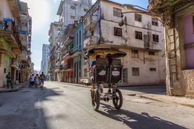 Havana, Küba - 13 Mayıs 2019: Canlı ve parlak güneşli bir sabahta Eski Havana Şehrinin sokaklarında bisikletli taksi şoförü.