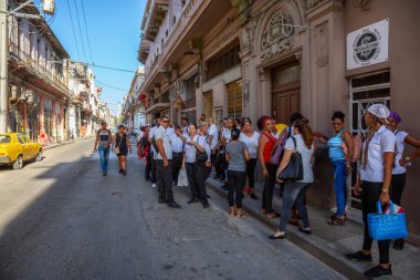 Havana, Küba - 13 Mayıs 2019: Parlak güneşli bir sabahta Eski Havana Şehrinin sokaklarında yemek için sırada bekleyen Kübalı lar.