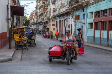 Havana, Küba - 13 Mayıs 2019: Canlı ve parlak güneşli bir günde Eski Havana Şehrinin sokaklarında motosikletsüren Kübalı adam.