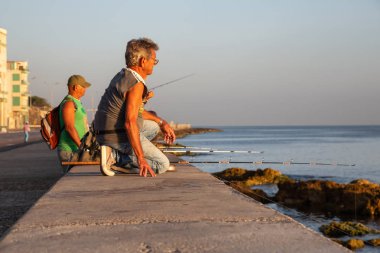 Havana, Küba - 14 Mayıs 2019: Küba halkı, Gıda Krizi Kıtlığı sırasında çekilen güneşli bir gün doğumu sırasında sabahın erken saatlerinde okyanusta balık tutuyor.