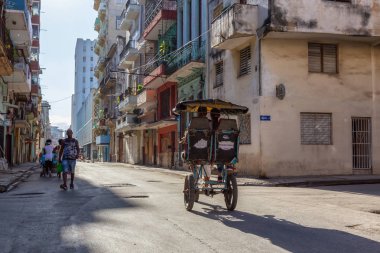Havana, Küba - 13 Mayıs 2019: Canlı ve parlak güneşli bir sabahta Eski Havana Şehrinin sokaklarında bisikletli taksi şoförü.