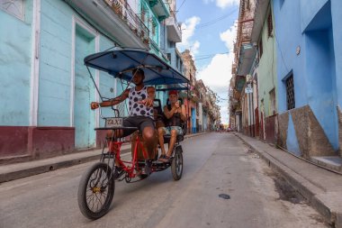 Havana, Küba - 13 Mayıs 2019: Canlı ve parlak güneşli bir sabahta Eski Havana Şehrinin sokaklarında bisikletli taksi şoförü.