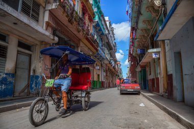 Havana, Küba - 13 Mayıs 2019: Canlı ve parlak güneşli bir sabahta Eski Havana Şehrinin sokaklarında bisikletli taksi şoförü.
