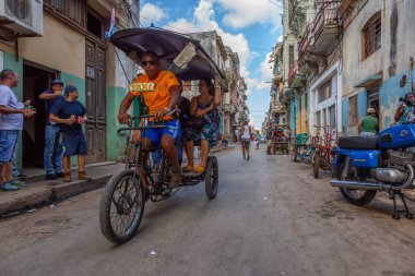 Havana, Küba - 13 Mayıs 2019: Canlı ve parlak güneşli bir sabahta Eski Havana Şehrinin sokaklarında bisikletli taksi şoförü.