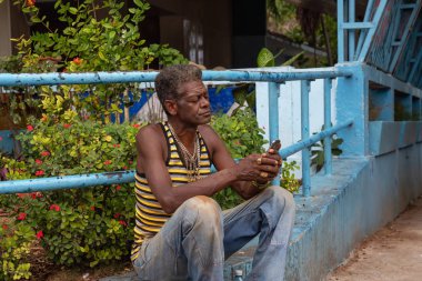 Havana, Küba - 15 Mayıs 2019: Kübalı adam Yağmurlu bir günde Eski Havana City sokaklarında Wifi Hotspot bir cep telefonu kullanıyor.