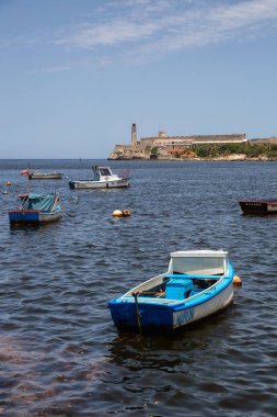Havana, Küba - 19 Mayıs 2019: Aydınlık ve güneşli bir günde arka planda deniz feneri bulunan marinada küçük balıkçı tekneleri.
