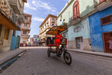 Havana, Küba - 14 Mayıs 2019: Canlı ve parlak güneşli bir sabahta Eski Havana Şehrinin sokaklarında bisikletli taksi şoförü.
