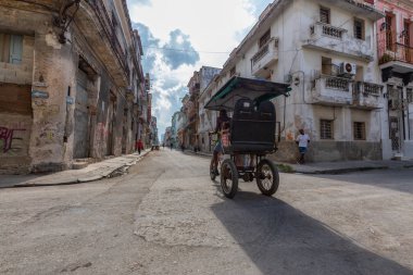 Havana, Küba - 14 Mayıs 2019: Canlı ve parlak güneşli bir sabahta Eski Havana Şehrinin sokaklarında bisikletli taksi şoförü.