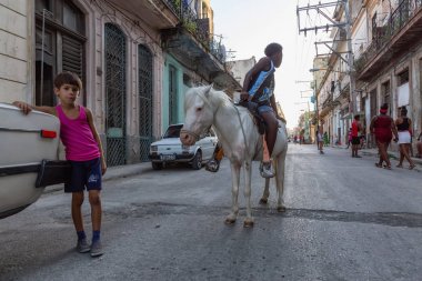 Havana, Küba - 27 Mayıs 2019: Eski Havana Şehrinin sokaklarında küçük bir atla genç Kübalı çocuklar, Küba'nın başkenti, parlak ve güneşli bir akşam.