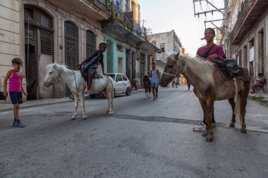 Havana, Küba - 27 Mayıs 2019: Eski Havana Şehrinin sokaklarında küçük bir atla genç Kübalı çocuklar, Küba'nın başkenti, parlak ve güneşli bir akşam.