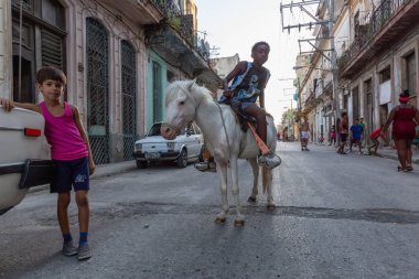 Havana, Küba - 27 Mayıs 2019: Eski Havana Şehrinin sokaklarında küçük bir atla genç Kübalı çocuklar, Küba'nın başkenti, parlak ve güneşli bir akşam.