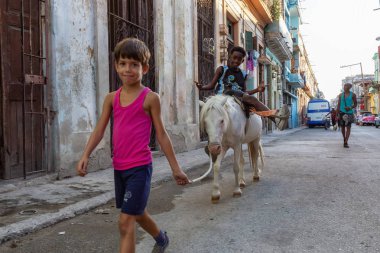 Havana, Küba - 27 Mayıs 2019: Eski Havana Şehrinin sokaklarında küçük bir atla genç Kübalı çocuklar, Küba'nın başkenti, parlak ve güneşli bir akşam.