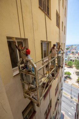 Havana, Küba - 16 Mayıs 2019: Kübalı adam sıcak güneşli bir günde Havana City'de bir binanın yan tarafında bir salıncak sahne üzerinde çalışıyoruz.