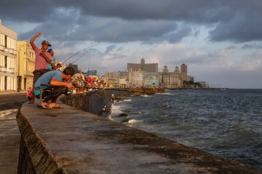 Havana, Küba - 25 Mayıs 2019: Küba halkı, Gıda Krizi Kıtlığı sırasında çekilen güneşli ve bulutlu gün doğumu sırasında sabahın erken saatlerinde okyanusta balık tutuyor.