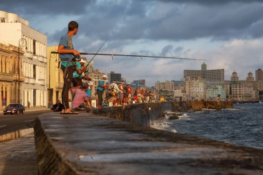 Havana, Küba - 25 Mayıs 2019: Küba halkı, Gıda Krizi Kıtlığı sırasında çekilen güneşli ve bulutlu gün doğumu sırasında sabahın erken saatlerinde okyanusta balık tutuyor.
