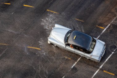 Havana, Küba - 29 Mayıs 2019: Yağmur yağdıktan sonra ıslak yolda seyreden eski bir otomobilin yukarıdan havadan görünümü.