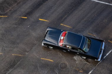 Havana, Küba - 29 Mayıs 2019: Yağmur yağdıktan sonra ıslak yolda seyreden eski bir otomobilin yukarıdan havadan görünümü.