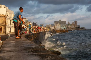 Havana, Küba - 25 Mayıs 2019: Küba halkı, Gıda Krizi Kıtlığı sırasında çekilen güneşli ve bulutlu gün doğumu sırasında sabahın erken saatlerinde okyanusta balık tutuyor.