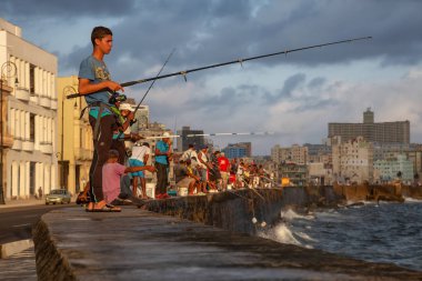 Havana, Küba - 25 Mayıs 2019: Küba halkı, Gıda Krizi Kıtlığı sırasında çekilen güneşli ve bulutlu gün doğumu sırasında sabahın erken saatlerinde okyanusta balık tutuyor.