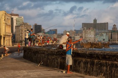 Havana, Küba - 25 Mayıs 2019: Küba halkı, Gıda Krizi Kıtlığı sırasında çekilen güneşli ve bulutlu gün doğumu sırasında sabahın erken saatlerinde okyanusta balık tutuyor.