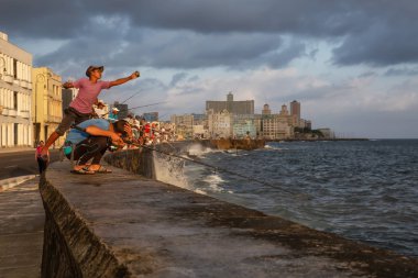 Havana, Küba - 25 Mayıs 2019: Küba halkı, Gıda Krizi Kıtlığı sırasında çekilen güneşli ve bulutlu gün doğumu sırasında sabahın erken saatlerinde okyanusta balık tutuyor.