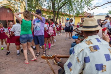 Trinidad, Küba - 6 Haziran 2019: İnsanlar canlı güneşli bir günde küçük bir Küba Kasabasının sokaklarında canlı müzik eşliğinde dans ediyorlar.
