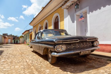 Trinidad, Küba - 6 Haziran 2019: Canlı güneşli bir günde küçük bir Küba Kasabasının sokaklarında eski bir Klasik Amerikan Arabasının Manzarası.