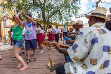 Trinidad, Küba - 6 Haziran 2019: İnsanlar canlı güneşli bir günde küçük bir Küba Kasabasının sokaklarında canlı müzik eşliğinde dans ediyorlar.