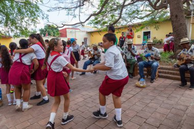 Trinidad, Küba - 6 Haziran 2019: Öğrenciler canlı güneşli bir günde küçük bir Küba Kasabası'nın sokaklarında canlı müzik eşliğinde dans ediyorlar.