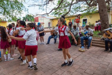 Trinidad, Küba - 6 Haziran 2019: Öğrenciler canlı güneşli bir günde küçük bir Küba Kasabası'nın sokaklarında canlı müzik eşliğinde dans ediyorlar.