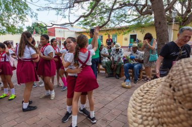 Trinidad, Küba - 6 Haziran 2019: Öğrenciler canlı güneşli bir günde küçük bir Küba Kasabası'nın sokaklarında canlı müzik eşliğinde dans ediyorlar.