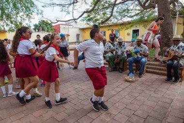 Trinidad, Küba - 6 Haziran 2019: Öğrenciler canlı güneşli bir günde küçük bir Küba Kasabası'nın sokaklarında canlı müzik eşliğinde dans ediyorlar.