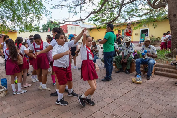 Trinidad, Küba - 6 Haziran 2019: Öğrenciler canlı güneşli bir günde küçük bir Küba Kasabası'nın sokaklarında canlı müzik eşliğinde dans ediyorlar.