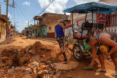 Trinidad, Küba - 08 Haziran 2019: Hareketli güneşli bir günde küçük bir Küba Kasabasının Kirli Caddesi'nde bisiklete binen Kübalılar.