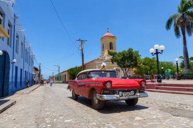 Trinidad, Küba - 6 Haziran 2019: Canlı güneşli bir günde küçük bir Küba Kasabasının sokaklarında eski bir Klasik Amerikan Arabasının Manzarası.