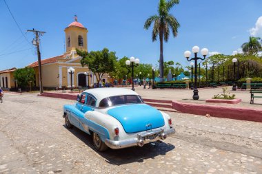 Trinidad, Küba - 6 Haziran 2019: Canlı güneşli bir günde küçük bir Küba Kasabasının sokaklarında eski bir Klasik Amerikan Arabasının Manzarası.