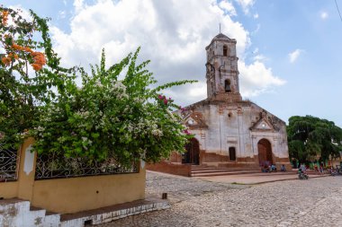Trinidad, Küba - 6 Haziran 2019: Canlı güneşli bir günde küçük bir turistik Küba Kasabasında eski bir kilisenin Sokak Görünümü.