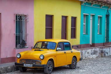 Trinidad, Küba - 6 Haziran 2019: Canlı güneşli bir günde küçük bir Küba Kasabası arka planda renkli binalar ile Eski Sarı Araba.