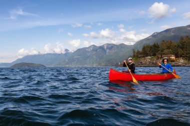 Kırmızı kano üzerinde çift maceracı kadın arkadaşlar bulutlu ve güneşli bir akşam boyunca Howe Sound kürek vardır. Horseshoe Bay yakınlarında çekilen, Vancouver'ın Batısı, Bc, Kanada.