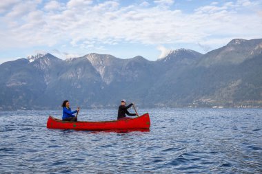 Kırmızı kano üzerinde çift maceracı kadın arkadaşlar bulutlu ve güneşli bir akşam boyunca Howe Sound kürek vardır. Bowen Adası yakınlarında çekilmiş, Vancouver'ın batısı, Bc, Kanada.