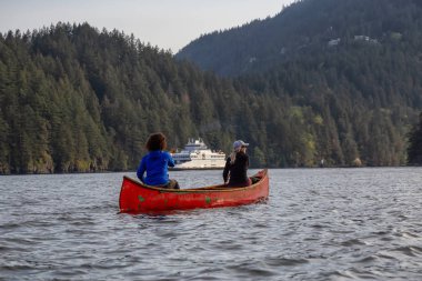 Kırmızı kano üzerinde maceracı arkadaşlar bulutlu bir gün boyunca arka planda Ferry Boat ile Howe Sound kürek vardır. Bowen Adası yakınlarında çekilmiş, Vancouver'ın batısı, Bc, Kanada.