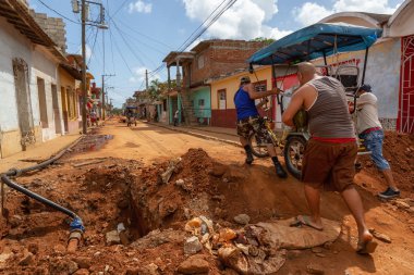 Trinidad, Küba - 08 Haziran 2019: Hareketli güneşli bir günde küçük bir Küba Kasabasının Kirli Caddesi'nde bisiklete binen Kübalılar.