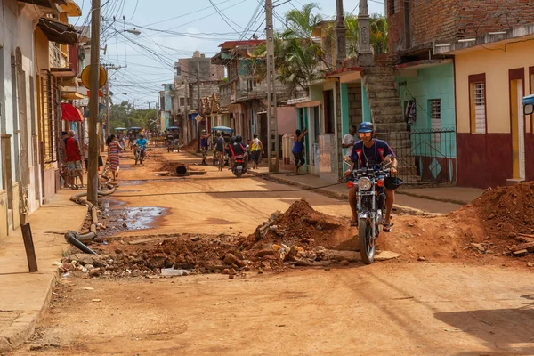 Trinidad, Küba - 08 Haziran 2019: Hareketli güneşli bir günde küçük bir Küba Kasabasının Kirli Caddesi'nde motosiklet sürmek.