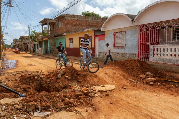 Trinidad, Küba - 08 Haziran 2019: Hareketli güneşli bir günde küçük bir Küba Kasabasının Kirli Caddesi'nde bisiklete binen Kübalılar.
