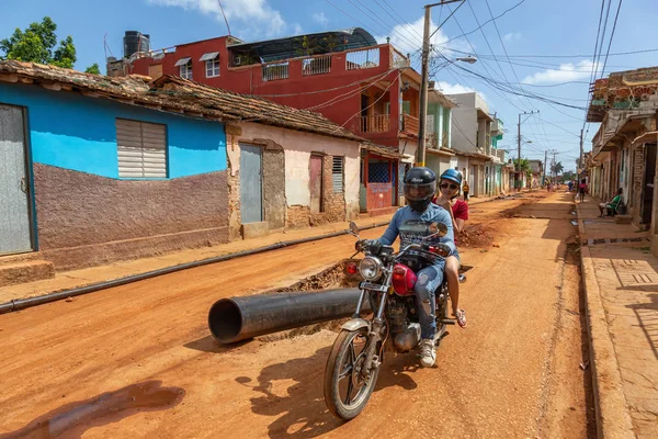 Trinidad, Küba - 08 Haziran 2019: Hareketli güneşli bir günde küçük bir Küba Kasabasının ıslak ve kirli caddesinde motosiklet sürmek.