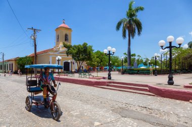 Trinidad, Küba - 6 Haziran 2019: Canlı güneşli bir günde küçük bir Küba Kasabası'nın sokaklarında bisikletli adam.
