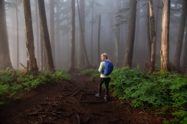 Maceracı bir kız sisli ve yağmurlu bir gün boyunca ormanda bir iz üzerinde yürüyüş. Alınan Cypress Provincial Park, Vancouver, British Columbia, Kanada.