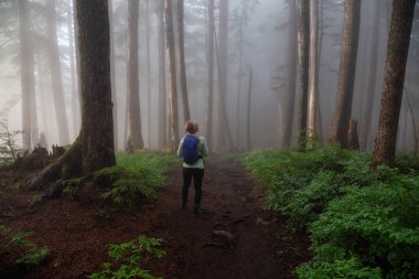 Maceracı bir kız sisli ve yağmurlu bir gün boyunca ormanda bir iz üzerinde yürüyüş. Alınan Cypress Provincial Park, Vancouver, British Columbia, Kanada.