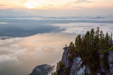 Canlı bir yaz gün batımı sırasında bulutlarla kaplı bir dağın tepesinde Kadın Hiker. St Mark Zirvesi'nin zirvesinde yer aldı, Batı Vancouver, British Columbia, Kanada.